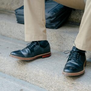Close-up of elegant black leather shoes paired with khaki pants on outdoor steps.