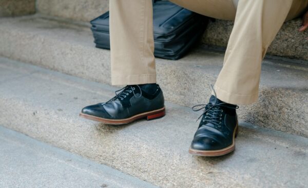 Close-up of elegant black leather shoes paired with khaki pants on outdoor steps.